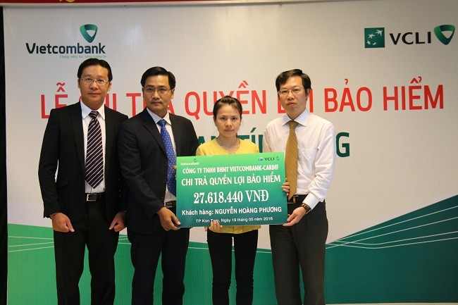 Ông Lê Tấn Lân - Giám đốc Vietcombank Kon Tum (ngoài cùng bên phải) trao quyền lợi bảo hiểm nhân thọ Bảo an Tín dụng cho người thụ hưởng Lê Thị Thùy.