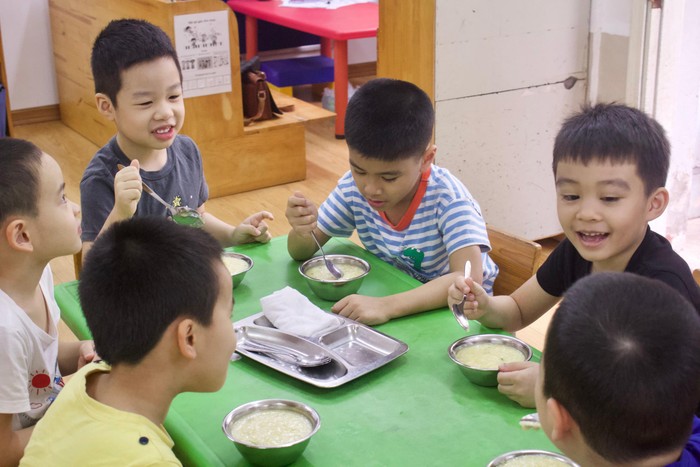 Các bé vui vẻ ăn uống, chơi đùa với nhau