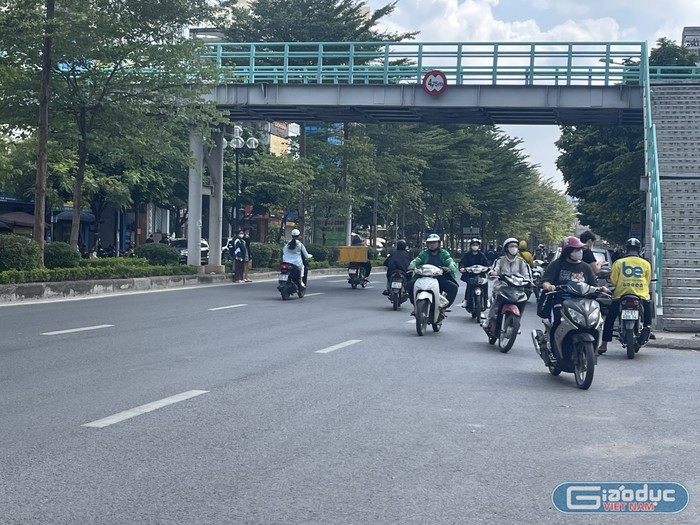 Trước cổng Trường Đại học Phương Đông, dù trên đường Trung Kính đã lắp đặt cầu vượt cho người đi bộ nhưng các sinh viên vẫn chọn cách đi bộ sang đường ngay dưới chân cầu. Các sinh viên khác cũng vô tư đi xe máy ngược chiều để đến trường.