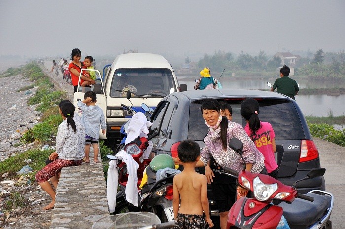 Trên đê, xe cộ và người đông đúc.