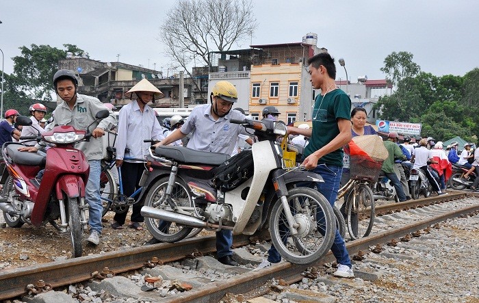 Nhiều người cố gắng dắt xe qua đường tàu để kịp giờ đưa sĩ tử đến phòng thi làm thủ tục.