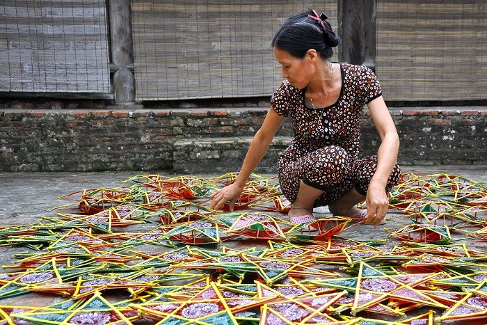 Tranh thủ trời có nắng, chị Mận (đội 7, xã Hồng Quang) lại mang đèn ra phơi để viền vàng của chiếc đèn vừa dán không bị thấm màu của giấy kính.