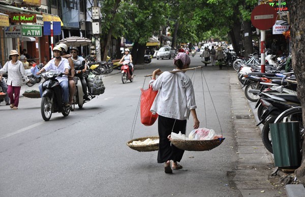 Gánh hàng rong lặng lẽ bước trong không khí ồn ào của phố xá.