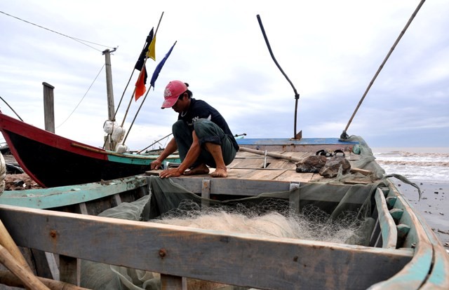 Anh Nguyễn Văn Huỳnh (xóm 3, xã Hải Lý, Hải Hậu, Nam Định) đang rỡ lưới trong thuyền để chiều ra khơi đánh ghẹ.