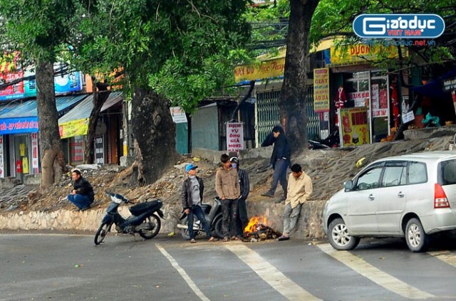 Tại cuối đường Hoàng Quốc Việt, một nhóm người lao động đang đốt lửa sưởi ấm khi chưa có việc