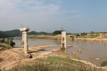 Những chiếc cầu có chiều dài khoảng 30m đang thi công dở. Tại cây cầu Phú Sơn, những nhịp cầu đang thi công nay bị bỏ lại dang dở. Những chiếc máy nằm im, không còn thấy công nhân nào làm việc ở đây. Hàng ngày, người dân muốn qua cầu đều phải trả tiền đò. Người dân ở đây đều mong muốn những chiếc cầu này được hoàn thành để đảm bảo an toàn mỗi khi qua sông. Tuy nhiên, chúng vẫn cứ bất động như thế! ( Ảnh: một cây cầu đang xây dựng dở bị bỏ lại).