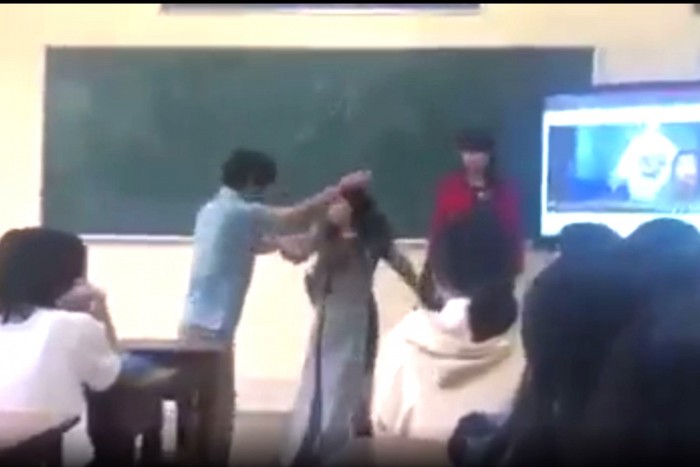 Hình ảnh cô giáo Hồ Thị Tâm mặc áo dài bị &quot;khóa tay&quot; mời ra khỏi lớp học. (Ảnh cắt từ clip).