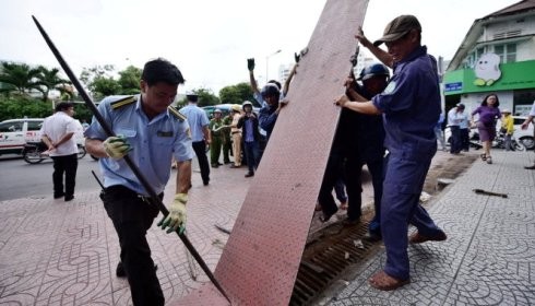 Quận 1 tiến hành tháo dỡ một tấm thép lấn chiếm vỉa hè của người đi bộ (ảnh: TTO)