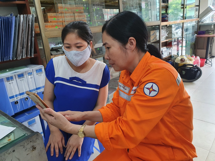 Công nhân Điện lực Mai Châu hướng dẫn khách hàng dịch vụ thanh toán tiền điện không dùng tiền mặt.