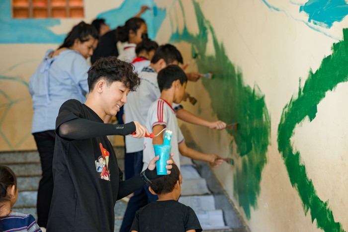 Các em học sinh cũng hào hứng tham gia tô màu để thay đổi diện mạo những bức tường cũ của nhà trường. Ảnh: NVCC.