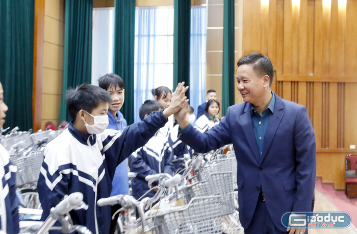 Nhà báo Nguyễn Tiến Bình trao tặng xe đạp và đập tay động viên các em học sinh.