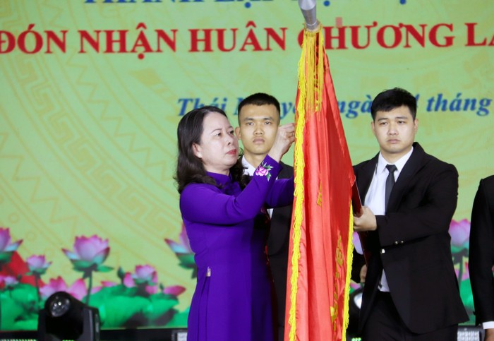 Quyền Chủ tịch nước Võ Thị Ánh Xuân gắn Huân chương Lao động hạng Nhất lên lá cờ truyền thống của Đại học Thái Nguyên.