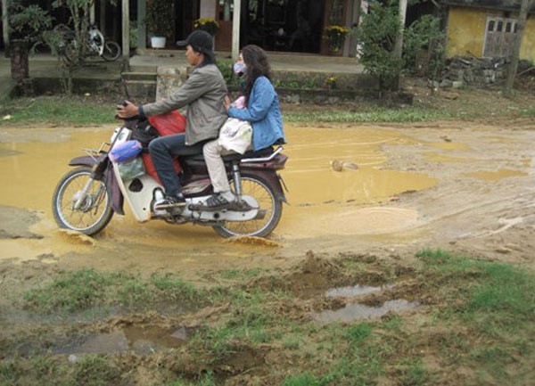 Để có thể đi chúc Tết, du xuân đầu năm, những cặp vợ chồng trẻ phải khó khăn, vất vả lắm mới có thể vượt qua đoạn đường đầy nước ngập, lầy lội bùn. (Ảnh: VNE).