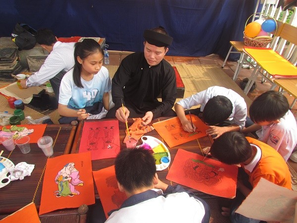 Nghệ nhân Đào Đình Trung đang dạy các em học sinh vẽ tranh đỏ