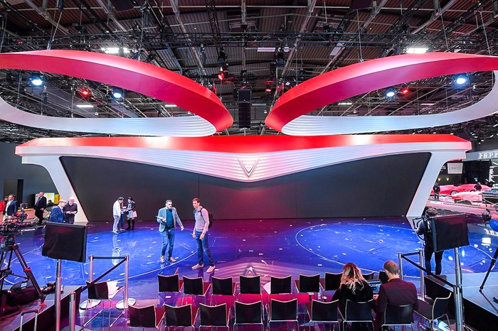 Logo hình chữ V nằm chính giữa sân khấu, hai cánh trải ra hai bên mô phỏng đèn xe “mắt hi” của VinFast. Viền đỏ chạy dài tại phần sải cánh của màn hình đem lại cảm giác mới mẻ, tràn đầy năng lượng.
