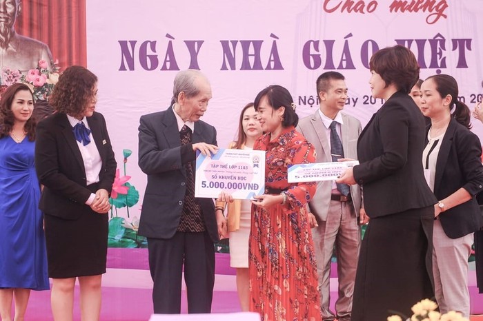 Chị Phạm Hải Anh (váy đỏ) phụ huynh học sinh lớp 11A3 Trường Trung học phổ thông Nguyễn Huệ - Bắc Từ Liêm – Hà Nội đại diện lớp trao số tiền đóng góp ủng hộ học sinh miền Trung.