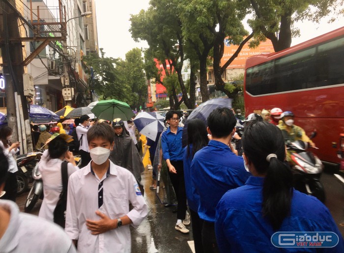 Không quản ngại trời mưa, đội tình nguyện nỗ lực hỗ trợ phân luồng giao thông. (Ảnh: Ngọc Mai).