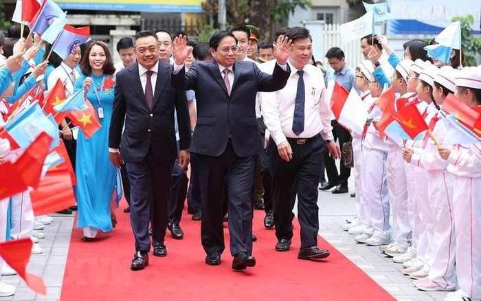 Các em học sinh Trường Tiểu học Đoàn Thị Điểm chào đón Thủ tướng Phạm Minh Chính và các đại biểu đến dự khai giảng. (Ảnh: Dương Giang/TTXVN)