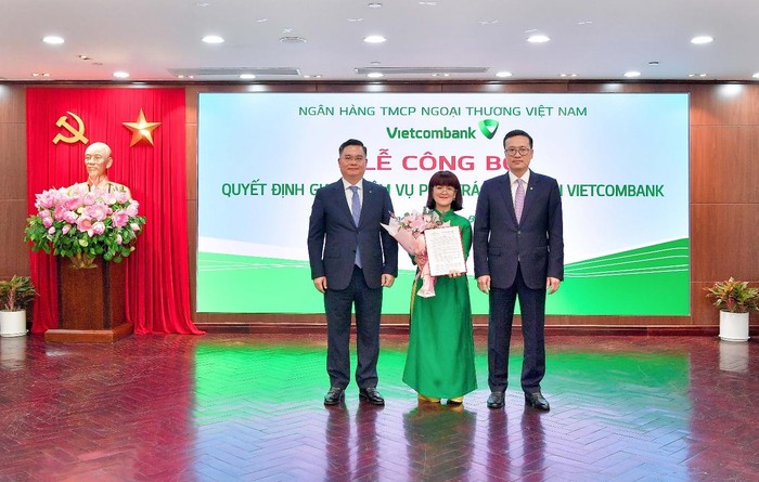 Bí thư Đảng ủy, Chủ tịch Hội đồng Quản trị Vietcombank Phạm Quang Dũng (bên phải) và Tổng Giám đốc Vietcombank Nguyễn Thanh Tùng (bên trái) trao Quyết định và tặng hoa chúc mừng bà Lê Thị Huyền Diệu - phụ trách Kế toán của Vietcombank.