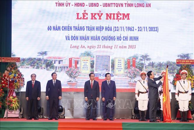 Chủ tịch nước Võ Văn Thưởng gắn Huân chương Hồ Chí Minh lên cờ truyền thống của tỉnh Long An. Ảnh: TTXVN