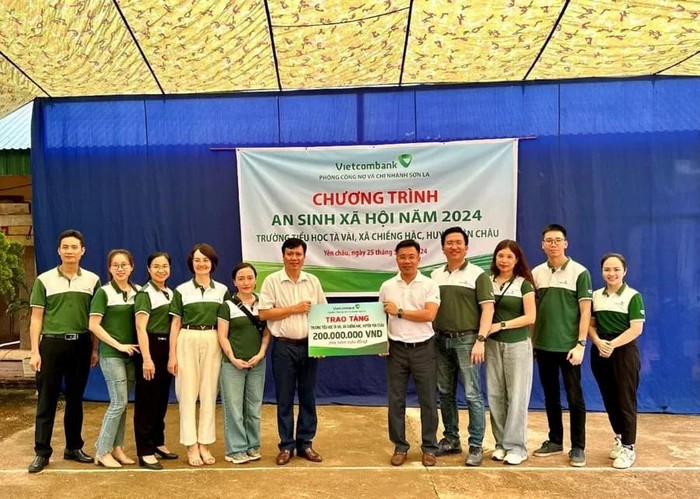 Đại diện đoàn Vietcombank trao biển tượng trưng tài trợ kinh phí cho đại diện Trường Tiểu học Tà Vài.