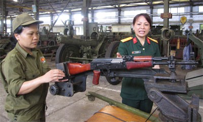 Trung tá QNCN Lê Thị Cẩm Tú (bên phải) hướng dẫn thợ sử dụng “Giá bắn thử súng tiểu liên AK sau sửa chữa”.