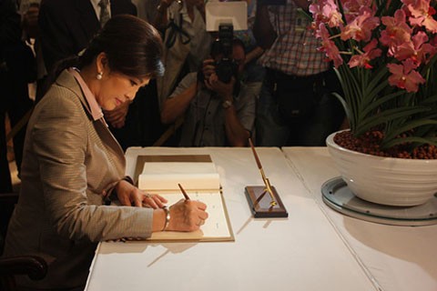 Thủ tướng Thái Lan Yingluck Shinawatra viết vào sổ lưu niệm trong buổi lễ công bố loài hoa phong lan mang tên bà tại Vườn Sinh học Singapore hôm 9/12. Ảnh: The Wall Street Journal.