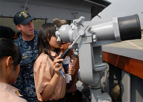 Một hoa tiêu trên tàu USS Vandegrift hướng dẫn cho các em học sinh các sử dụng ống nhòm. Ảnh: US Navy