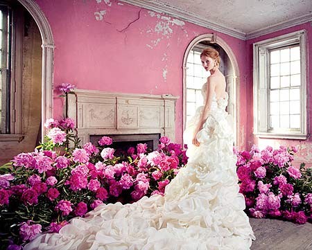 Chiếc váy trắng bằng lụa và vải organza với phần đuôi váy dài hệt như một vườn hoa đua nở là kiệt tác của nhà tạo mẫu Manuel Mota. Màu hồng phớt thơ mộng tạo cho cô dâu vẻ đẹp vừa ngây thơ vừa quyến rũ.