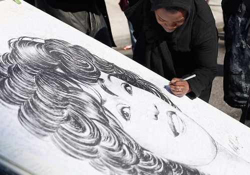Người hâm mộ ký tên lên bức chân dung Whitney Houston của họa sĩ Mark G - Ảnh: AP