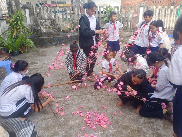 Các bạn học sinh cùng nhau làm cây đào đón tết. (Ảnh: NTCC)