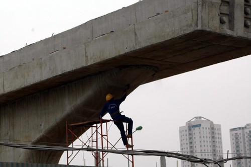 Người đứng chênh vênh không rào chắn, người đu bám trên không, người ngồi trên giàn giáo,người tiếp sắt, thép... Ảnh: Một tay bám vào giàn giáo một tay mang máy mài bê tông