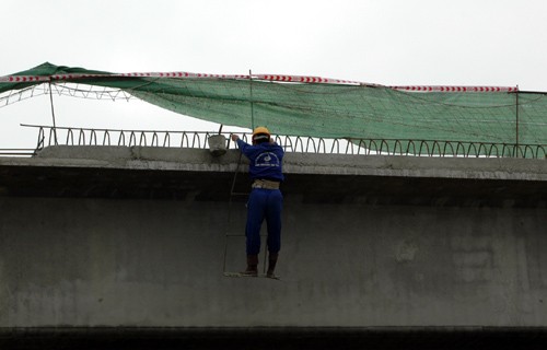 Công nhân vừa đu bám bên công trình vừa tiếp nhận nguyên vật liệu như: sắt, thép trừ cần cẩu đưa tới. Ảnh: Đu bám trên không trung ở độ cao gần 20m