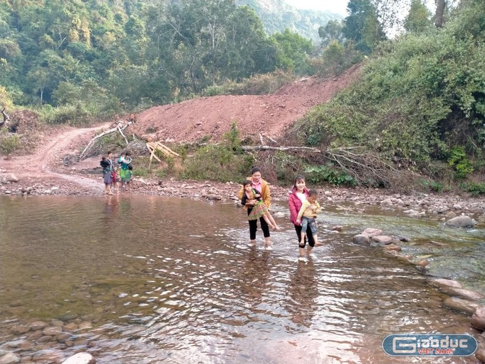 Buổi sáng cô Kim, cô Liệu đón học sinh qua suối lên lớp.