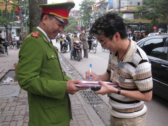 Có vẻ như Mr Đàm viết thêm điều gì đó khiến anh công an vui cười tít mắt...