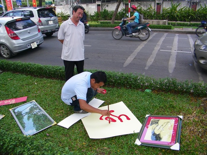 Khách hàng Hoàng Ngọc Thạch đang “xin chữ” (hay mua chữ?) của “ông đồ” Trần Phong. Anh Thạch đang chờ Phong viết xong chữ “lộc”, với giá 150 ngàn. Anh Thạch cho biết: “Vợ tôi tên Lộc nên tôi muốn dành món quà bất ngờ tặng cho bà ấy trong dịp tết”.