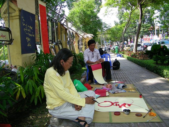 Vẻ mặt đăm chiêu của “ông đồ” Bùi Hiến trước khung cảnh hịu quạnh khách. Anh là anh, em chú bác ruột với thi sĩ trứ danh Bùi Giáng (bố của anh là anh ruột của bố thi sĩ). Anh chính là người “sáng lập” ra góc phố ông đồ trên đường Trương Định. 11 lần tết đến, anh đều đã ngồi ngay góc phố này