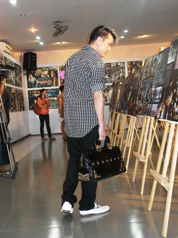 Không chỉ xem ảnh của mình, Mr Đàm còn xách…túi đi xem ảnh của các nhân vật nổi tiếng khác. Nếu để ý, đôi giày Mr Đàm mang cũng là “hàng hiệu”, thuộc nhãn hiệu giày thời trang nổi tiếng thế giới Dolce Gabbana.