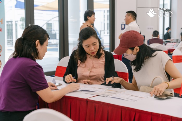 Một phụ huynh đang thực hiện các thủ tục đăng ký học cho con tại Ngày hội thông tin – &quot;Hành trình vững bước tương lai&quot;