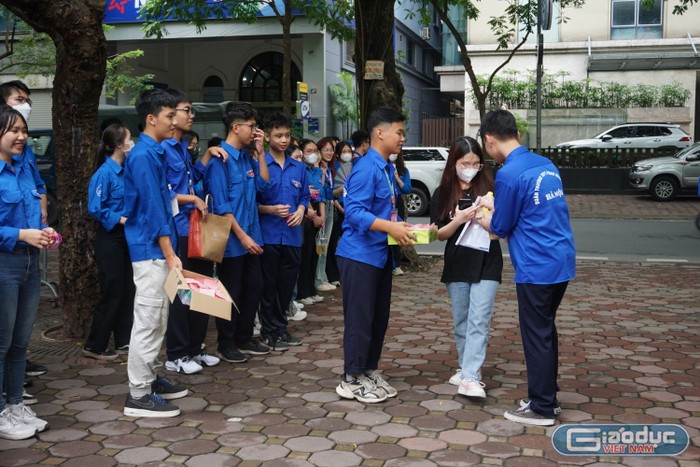 Tình nguyện viên tặng quà cho thí sinh trước khi vào làm thủ tục dự thi (điểm thi Trường Trung học phổ thông Phan Đình Phùng). Ảnh: Minh Phạm