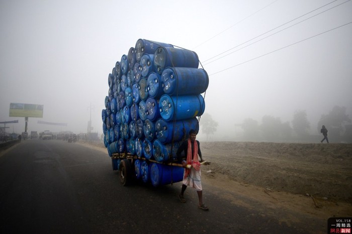 Một người đàn ông Bangladesh kéo chiếc xe chất đầy thùng phuy trống gần thủ đô Deca ngày 20/12