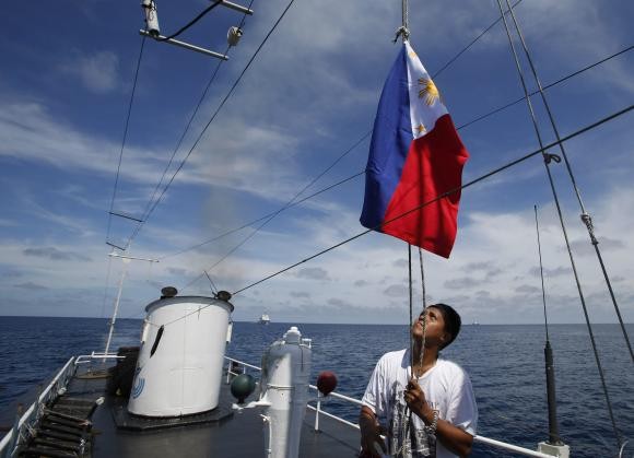 Một người lính hải quân Philippines mặc đồ dân sự làm lễ hạ cờ trên con tàu tiếp tế khi chiều xuống.