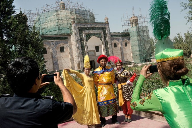 Khách du lịch chụp ảnh trong trang phục của hoàng đế Càn Long và Hàm Hương trước khu di tích được cho là lăng mộ của Hàm Hương/Iparhan ở Kashgar, Tân Cương sau khi được nghe kể truyền thuyết về nàng (do Bắc Kinh sáng tác).