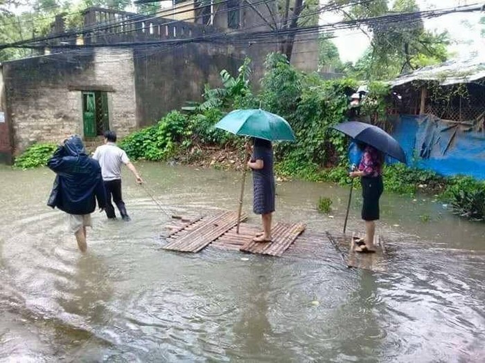 Hình ảnh bà Nguyễn Thị Tâm, Chủ tịch ủy ban nhân dân phường Đông Thọ cùng cấp dưới đang đứng trên bè tự chế cho người khác kéo đi xem lũ