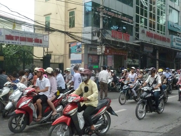 Phụ huynh đứng chờ đông tràn ra hai bên đường, trong khi người đi đường qua lại tấp nập