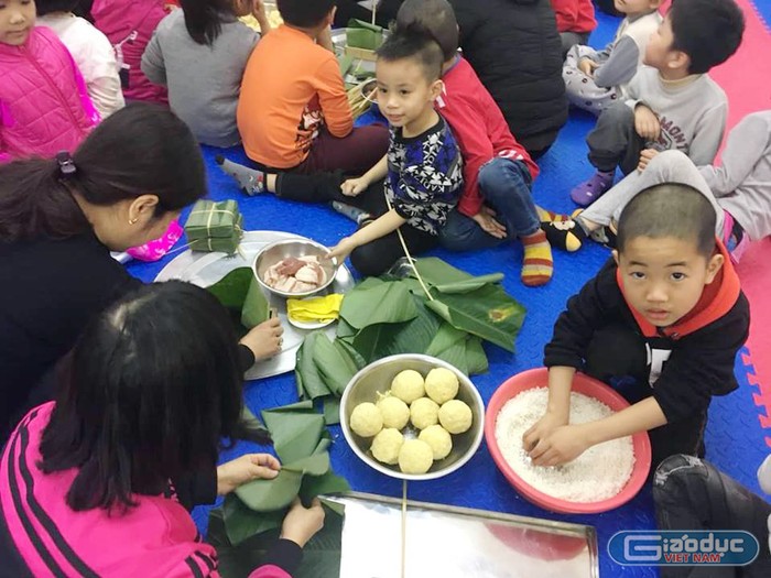 Học sinh trường Mầm non Bông Sen được hướng dẫn, tự tay gói bánh chưng (Ảnh: Lã Tiến)