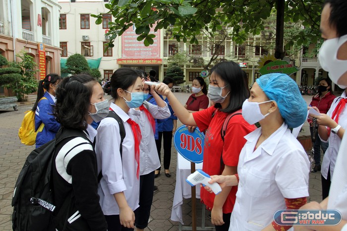 Các em học sinh Trường Trung học cơ sở Tô Hiệu được đo thân nhiệt từ cổng trường (Ảnh: Lã Tiến)