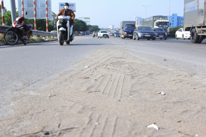 Trên mặt cầu Thanh Trì ngoài biển thông báo cho phương tiện về việc đường mấp mô, nơi đây còn tồn tại nhiều vật liệu xây dựng, rác thải rơi vãi gây nguy hiểm cho người tham gia giao thông. (Ảnh: Mạnh Đoàn)