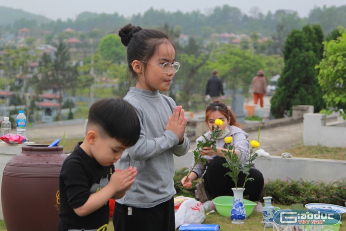 Hai người con của anh Hùng lễ trước mộ của ông nội. (Ảnh: Mạnh Đoàn)