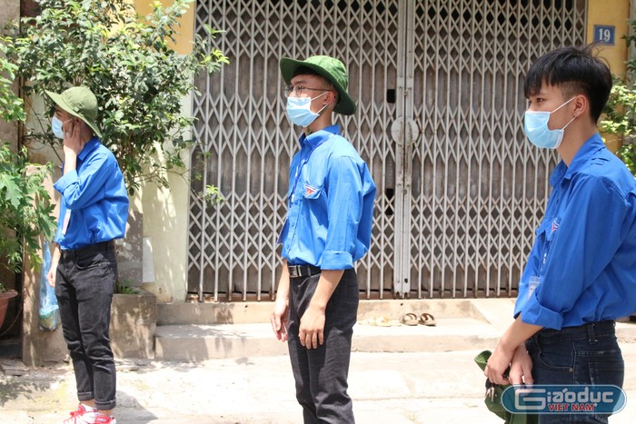 Lý Anh Vũ (giữa) cùng bạn bè tham gia nhiệm vụ phân luồng giao thông, nhắc nhở phụ huynh thí sinh thực hiện giãn cách an toàn. (Ảnh: Phạm Minh)